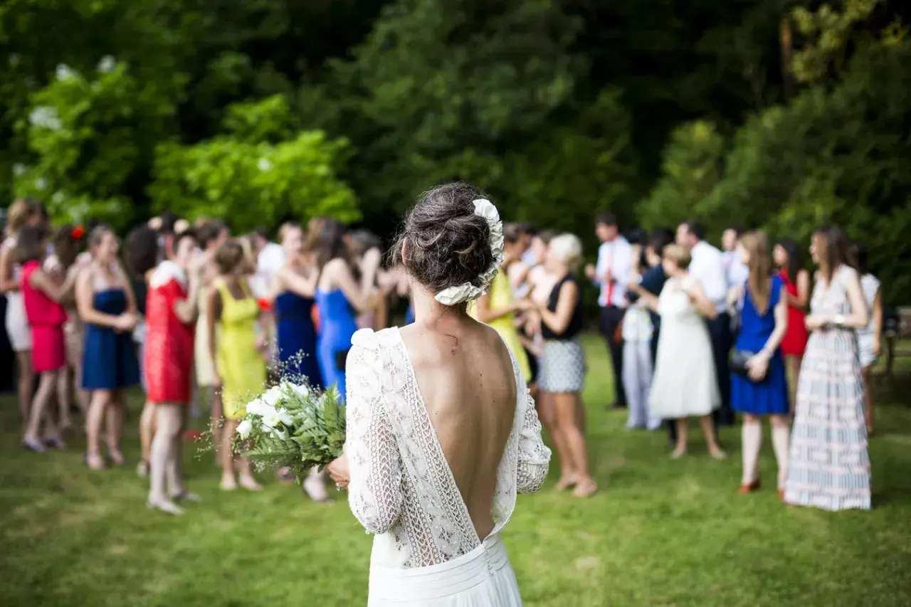 Novia con ramo, rodeada de invitados en los preparativos de boda.
