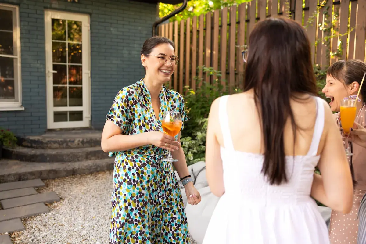 Mujeres riendo y brindando en una fiesta temática al aire libre.