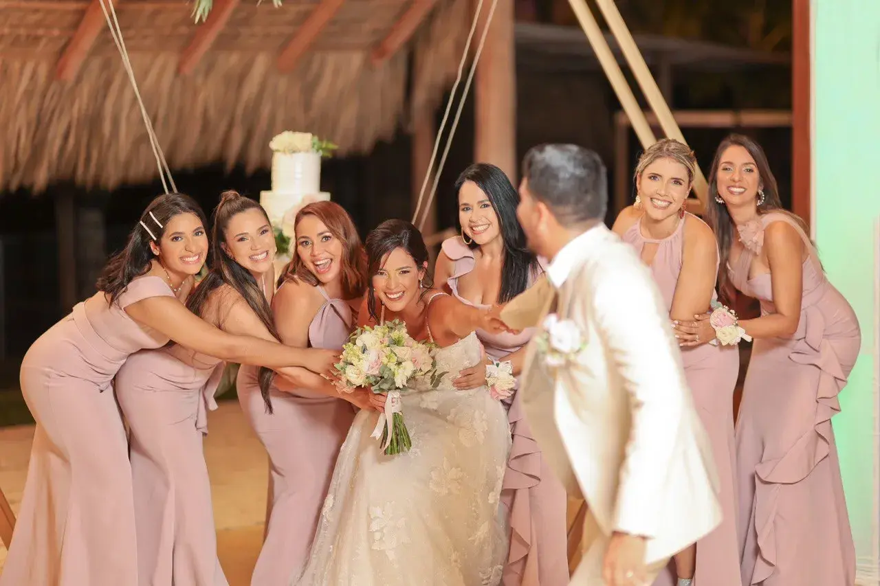 La novia y sus damas de honor ríen juntas, rodeando a la feliz pareja en un día especial.