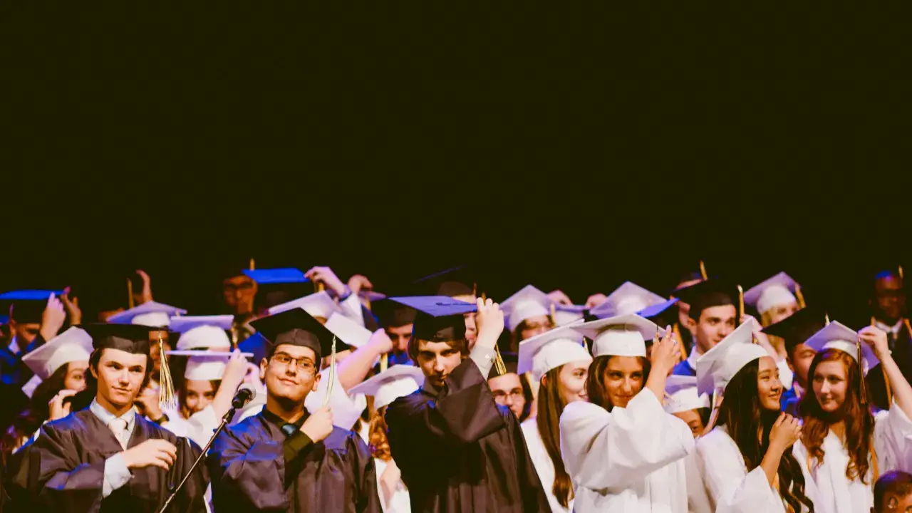 Estudiantes celebran su graduación universitaria, ajustándose togas y birretes.