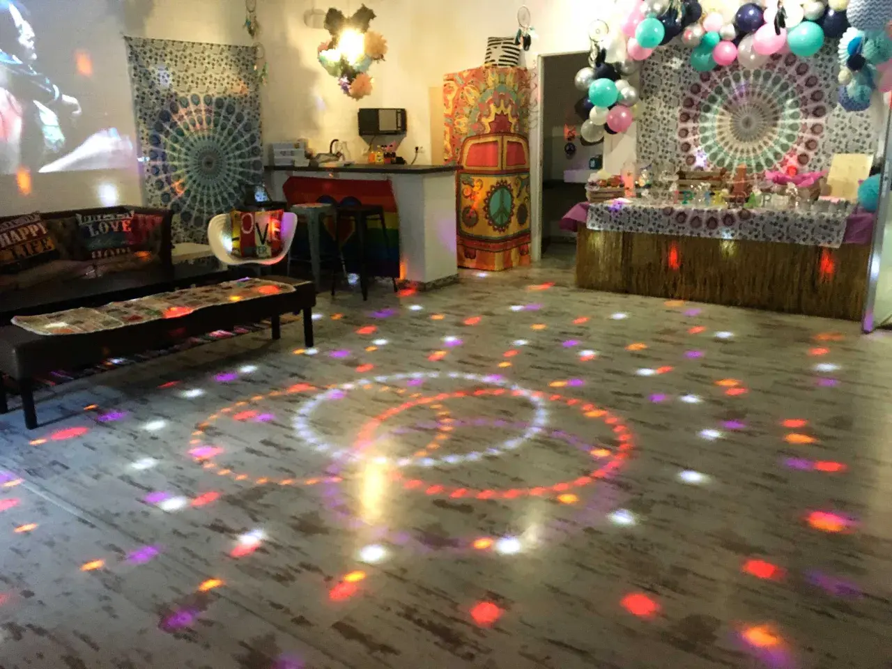 Un salón decorado con estilo hippie para unas **fiestas de cumpleaños de adultos divertidas**. Luces de discoteca proyectan círculos de colores sobre el suelo.
