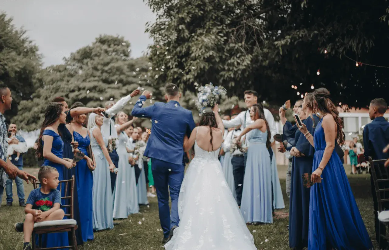 Novios celebran con confeti. El dresscode que es, se ve en los vestidos azules de las damas y trajes oscuros de los caballeros.