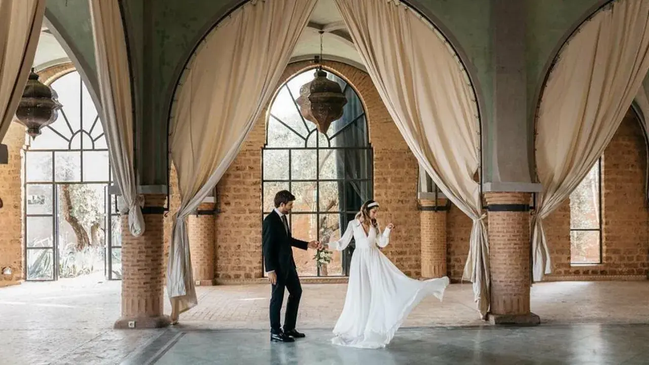 Novios bailan en un salón con arcos y cortinas, celebrando que las bodas son a los 10 años.