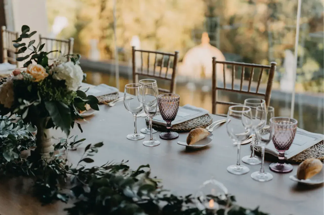 Mesa de boda romántica vintage con flores, copas de cristal y panecillos.