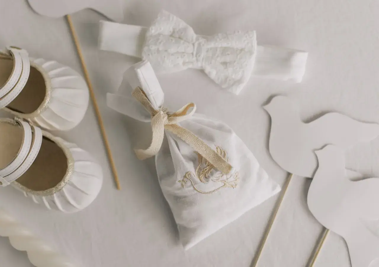 Detalles para un bautizo: zapatos de bebé, diadema de encaje, bolsita bordada y palomas. Ideas para donde celebrar bautizo.