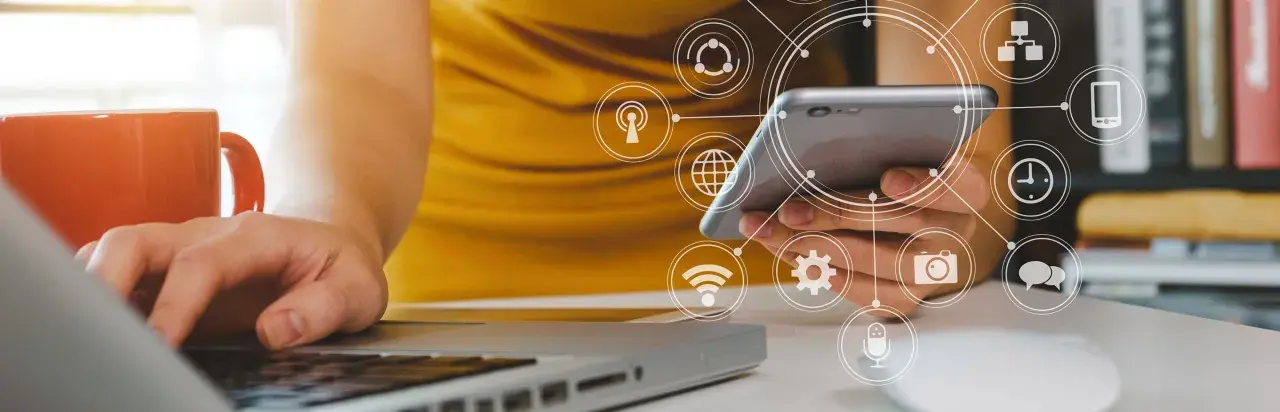 Persona usando un móvil y portátil con iconos de analítica digital superpuestos.