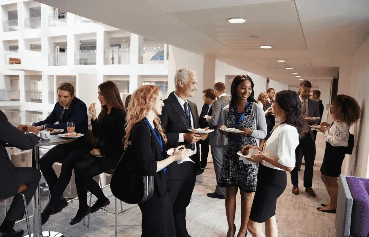 Profesionales conversan y disfrutan de un cóctel en un evento corporativo. Ejemplos de networking y colaboración.