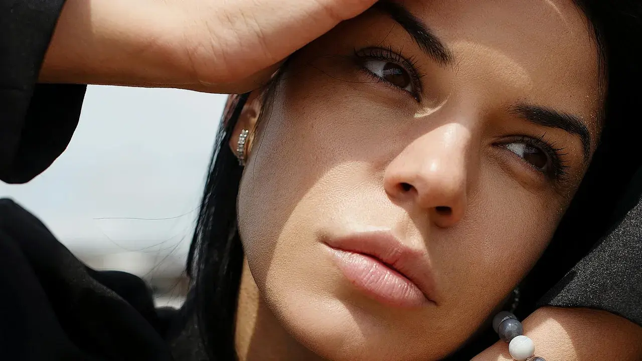 Primer plano de una mujer pensativa, con la mano en la frente, como si estuviera dándole vueltas a las cosas, significado en su mirada.