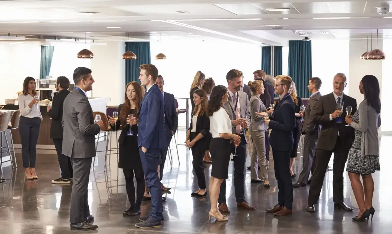 Gente en un evento de networking, conversando y bebiendo. Ejemplos de c&oacute;mo interactuar en convenciones.