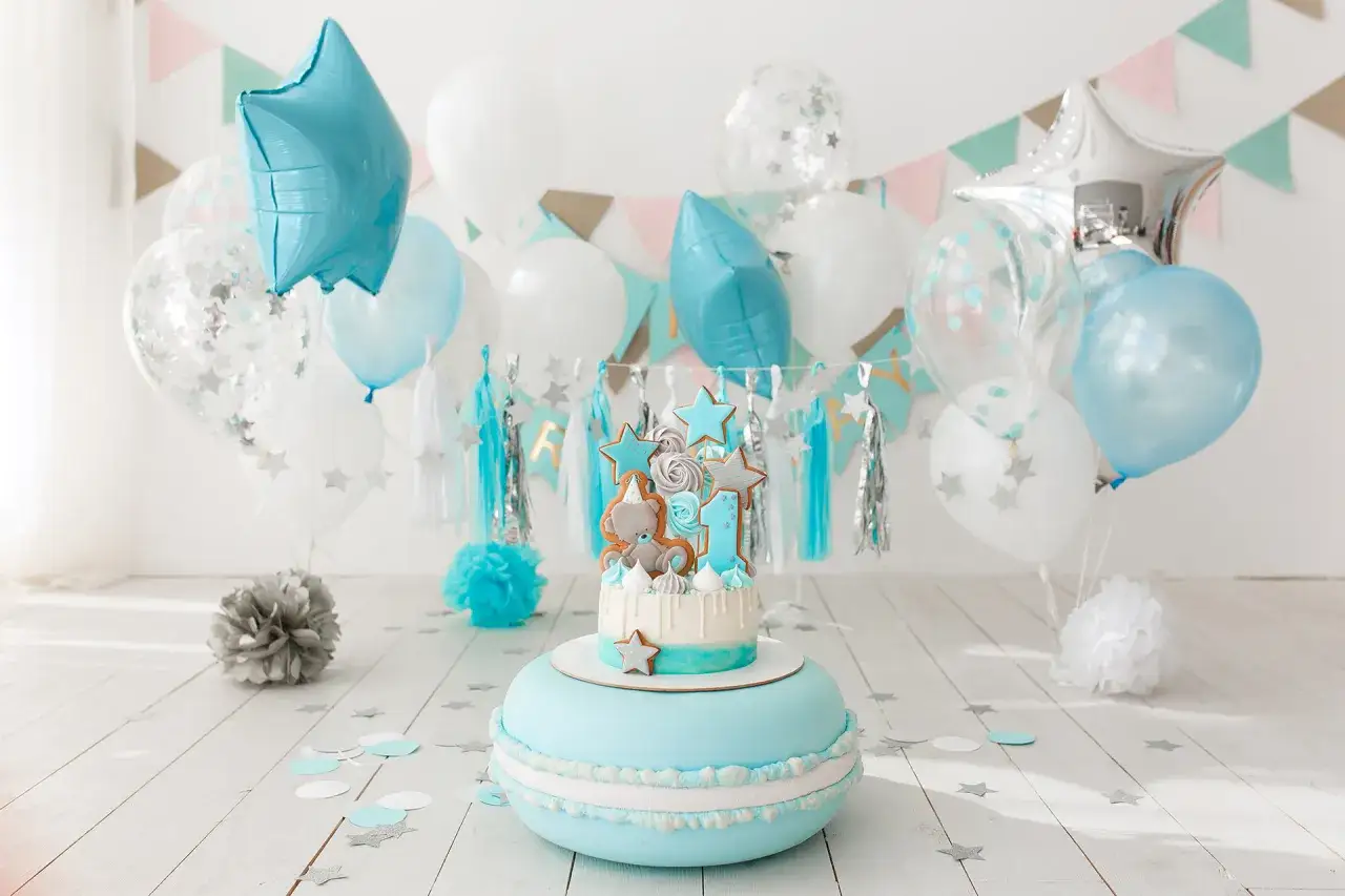 Un pastel de primer cumplea&ntilde;os con un oso de peluche y estrellas, rodeado de globos azules y blancos, perfecto para celebrar un cumplea&ntilde;os.