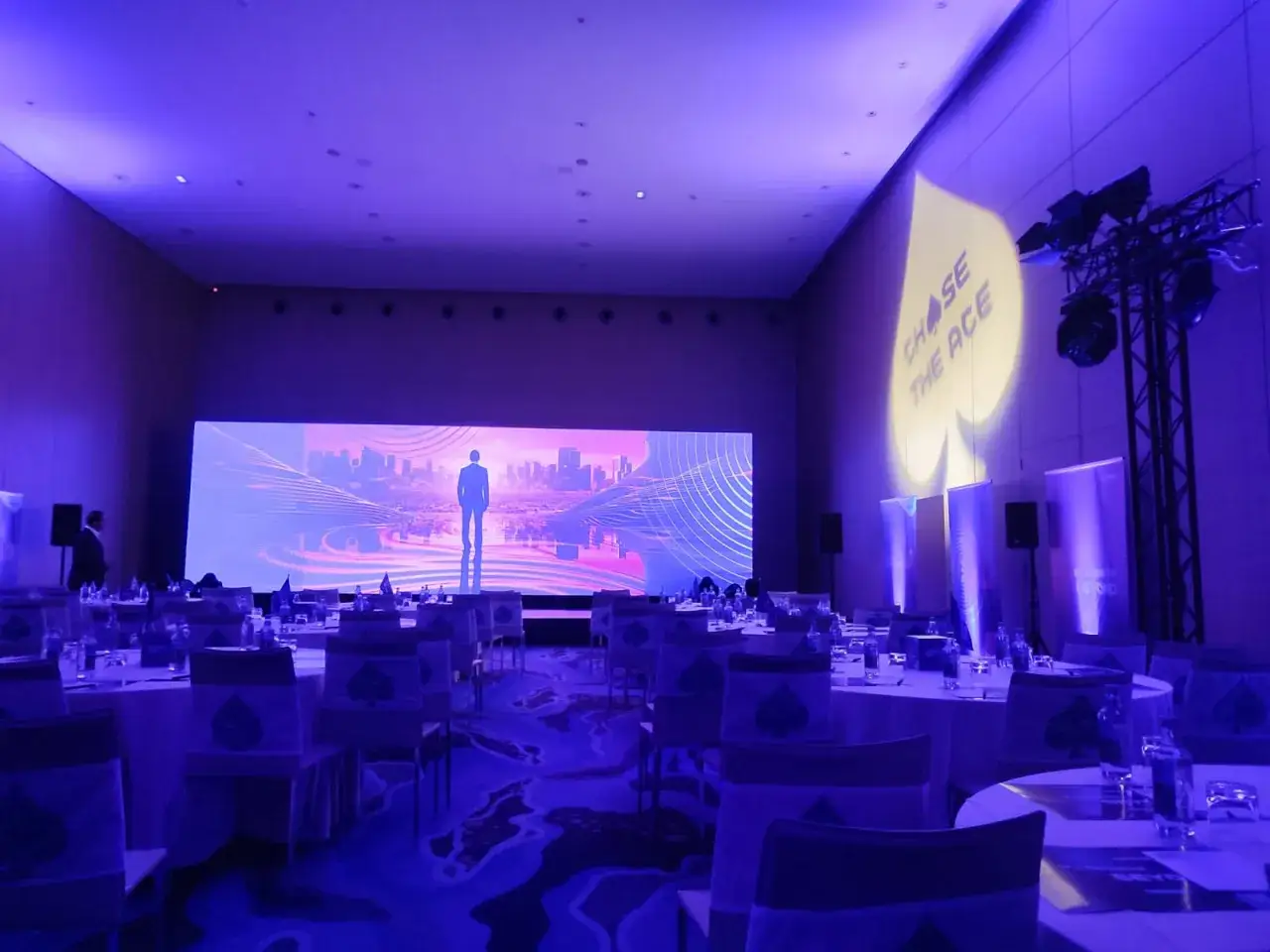 Sal&oacute;n preparado para eventos de empresa, con pantallas gigantes y mesas dispuestas. El logo 