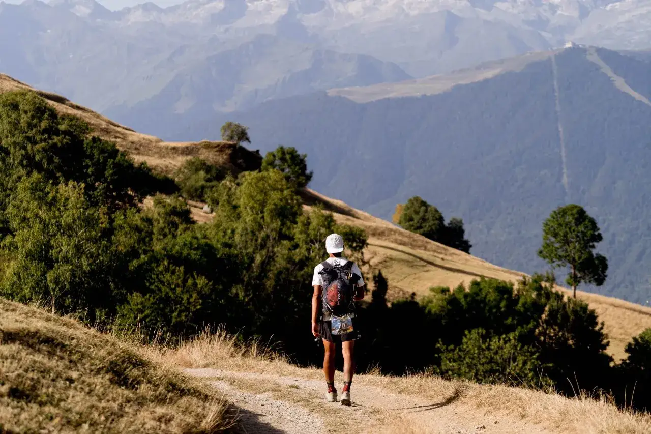 Corredor de monta&ntilde;a avanza por un sendero polvoriento, con un paisaje de colinas y monta&ntilde;as a pesar de las adversidades.