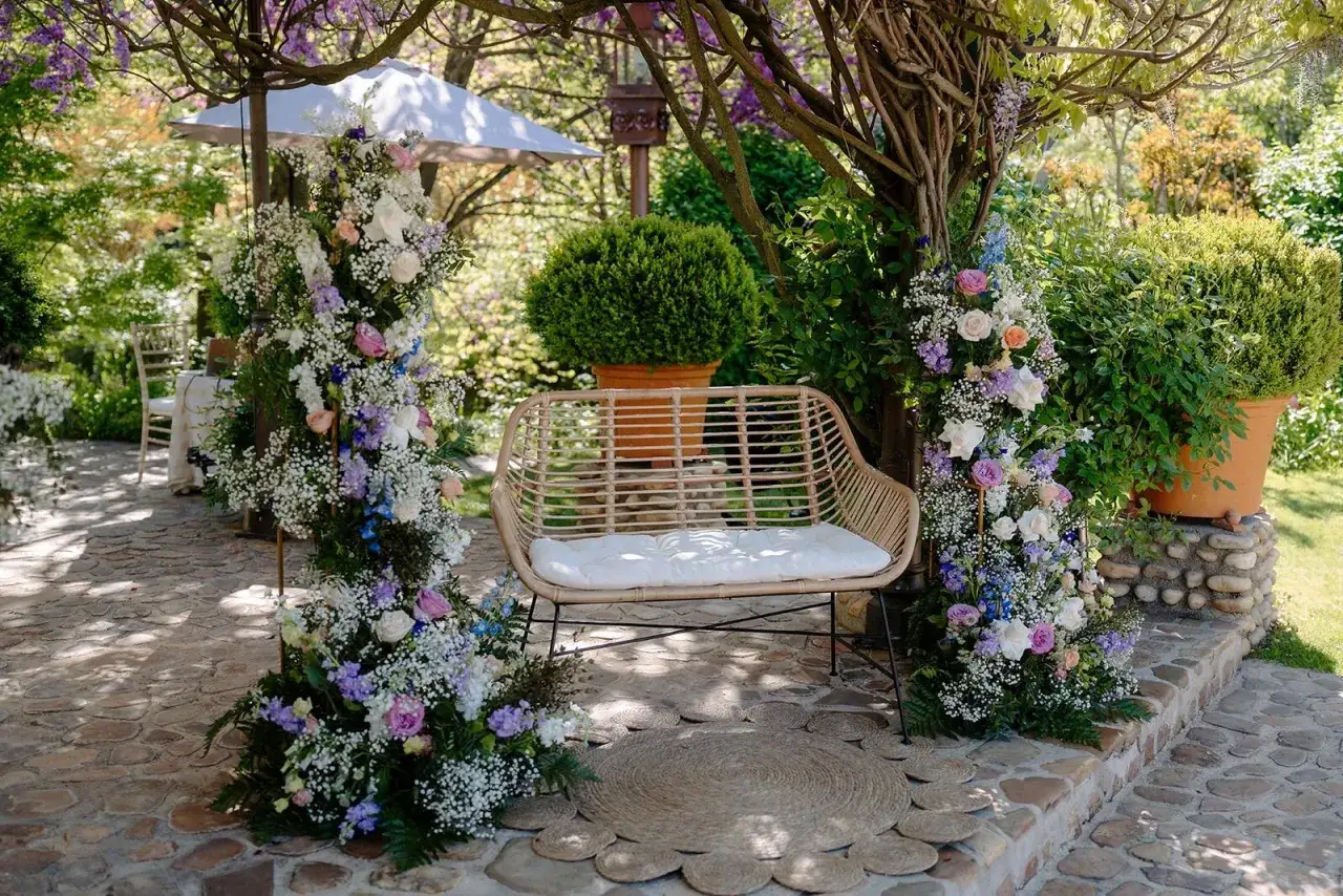 Un rinc&oacute;n id&iacute;lico para bodas al aire libre, con arcos florales y un banco de mimbre. Los estilos de boda naturales y rom&aacute;nticos se reflejan en la decoraci&oacute;n.