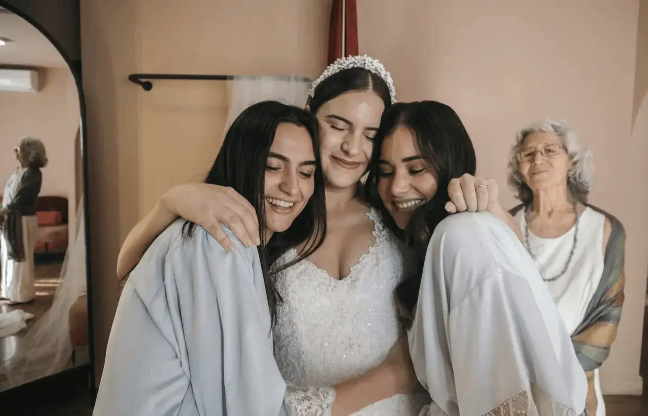 Las damas de honor en España abrazan a la novia, radiantes de felicidad. Una abuela las observa con ternura.