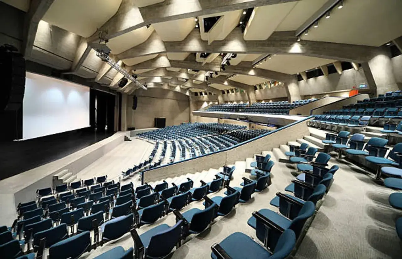Gran auditorio moderno con asientos azules, listo para una convención empresarial.