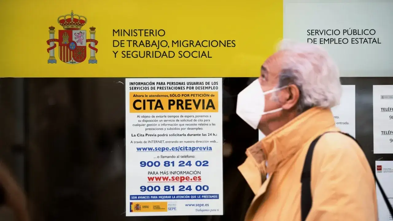 Un hombre con mascarilla mira un cartel del SEPE que explica cómo solicitar el paro: