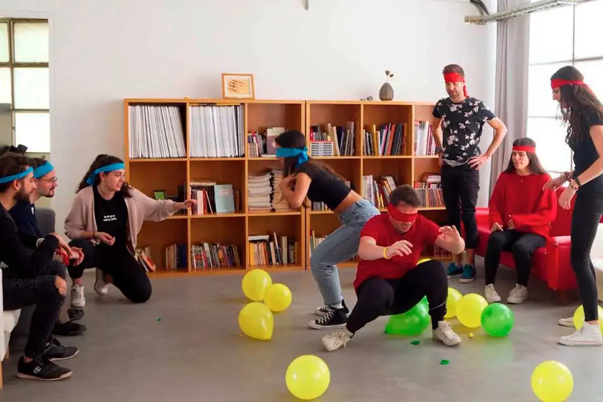 J&oacute;venes con vendas en los ojos juegan a explotar globos, una idea divertida de qu&eacute; hacer en una fiesta.