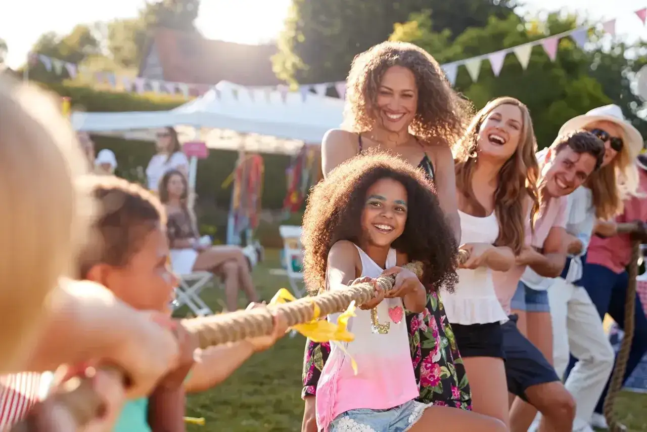 Ni&ntilde;os y adultos compiten en una cuerda, celebrando un d&iacute;a familiar en empresas.